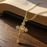 Gold cross pendant necklace beside an open Bible