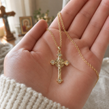 Gold cross pendant necklace held in hand