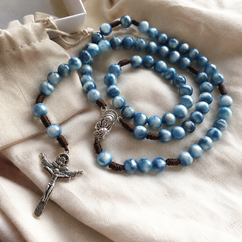 Close-up of blue acrylic beads braided cord crucifix and Marian medal